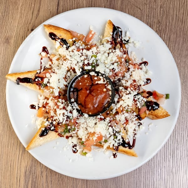 Italian bruschetta with diced tomatoes, feta cheese, balsamic glaze, and a side of red sauce.