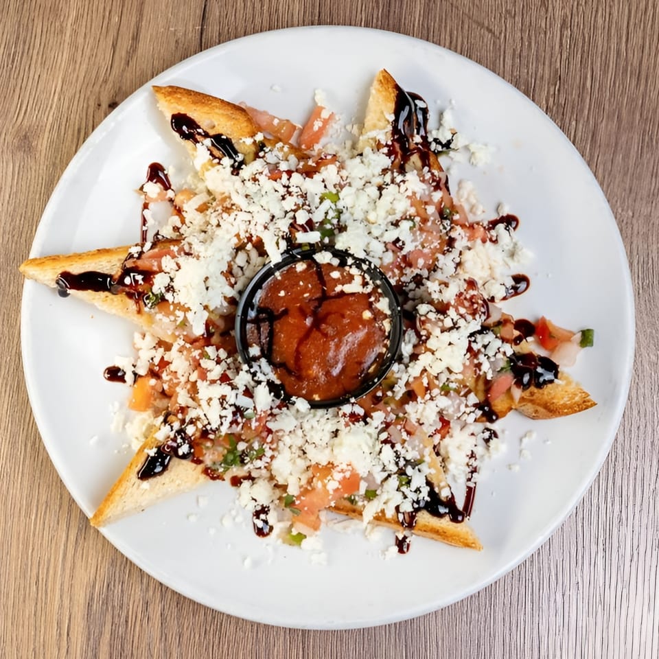 Italian bruschetta with diced tomatoes, feta cheese, balsamic glaze, and a side of red sauce.