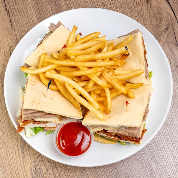 Italian sandwich with meat, lettuce, and fries, served with a side of ketchup.